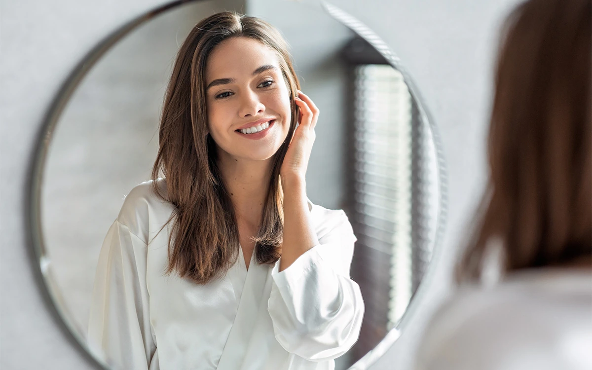 Attractive young woman admiring her reflection after cosmetic procedure