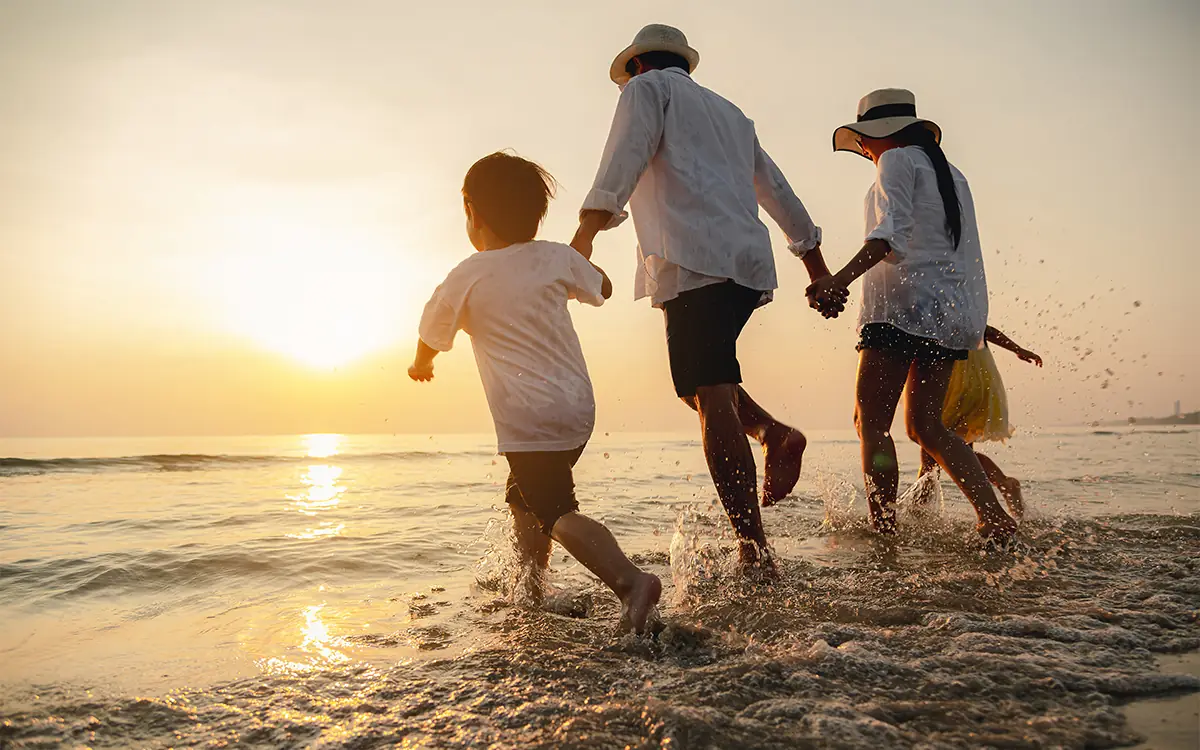 Family jumping in ocean waves during sunset