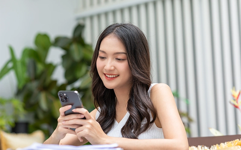 Smiling Asian woman looking at phone
