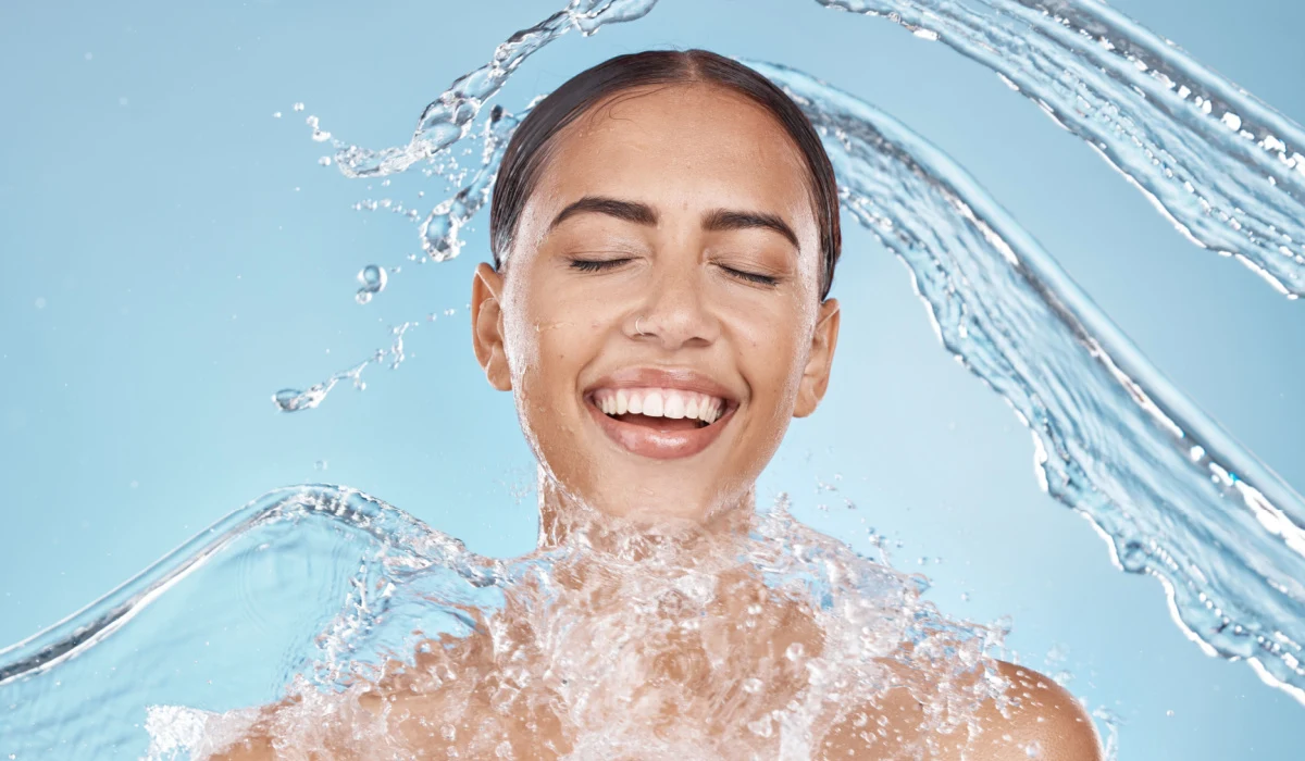 woman with water splashing on her face to show hydration